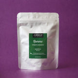 Envase Doypack plateado de Romero Amman Tea Blends con etiqueta verde para combatir el cansancio, sobre fondo morado.
