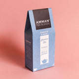 Caja de té Jasmine Tea de Amman Tea Blends, té blanco con flores de jazmín, empaque celeste sobre fondo rosado.