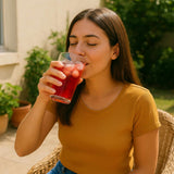 Mujer disfrutando un vaso de té helado con hielo al aire libre, bebida refrescante de verano.