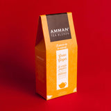 Caja de té verde con jengibre Amman Tea Blends en envase naranja sobre fondo rojo, infusión de sabor intenso y ligeramente picante.